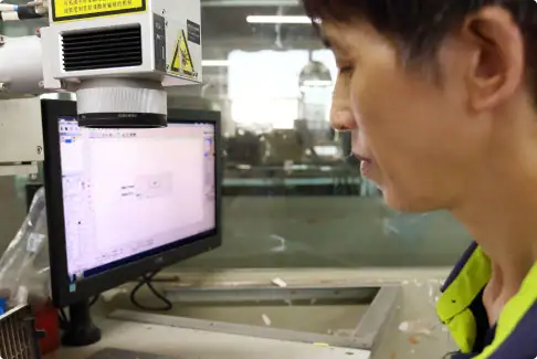 Technician working on a computer-controlled machine in a manufacturing facility, focusing on precision engineering and quality control processes.