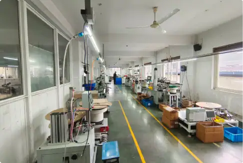 Laboratory workspace with scientific equipment, glassware, and supplies arranged along a long table in a well-lit room. The space appears organized for scientific experiments or research activities.