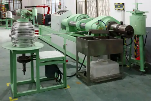 Industrial metal wire manufacturing machine with coiled wire spool and processing equipment.