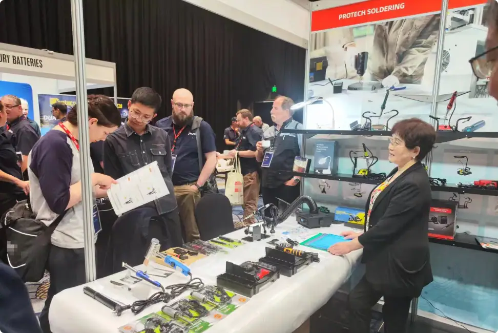 Advanced soldering tools and electronic components displayed at a trade show booth. Attendees explore the latest in soldering technology, including PROTECH soldering solutions, with industry professio.