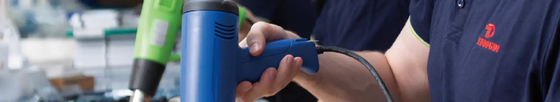 Cordless drill being operated by a person in a workshop setting, showcasing power tools for construction or DIY projects.
