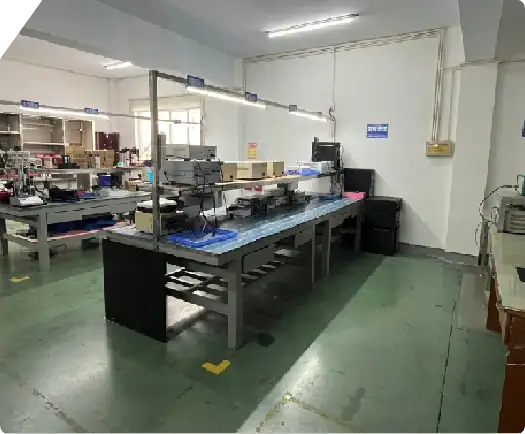 Electronic manufacturing workspace with assembly stations, tools, and equipment for assembling electronic devices.