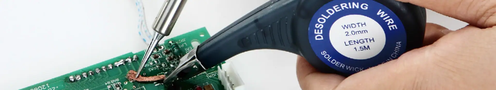 Close-up of a soldering iron working on a green circuit board with electronic components, demonstrating precision soldering for electronics repair or assembly.