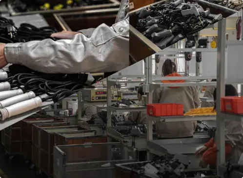 Up of a worker assembling electronic components on a production line with various tools and equipment.