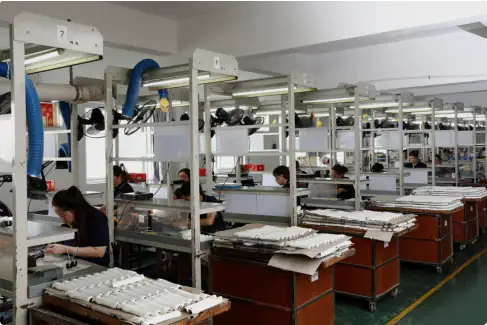 Assembly line workers assembling electronic devices in a manufacturing plant.