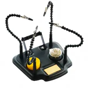 Image shows a soldering helping hands tool with adjustable arms, alligator clips, a sponge, and a soldering iron stand, designed to assist in precise soldering tasks.