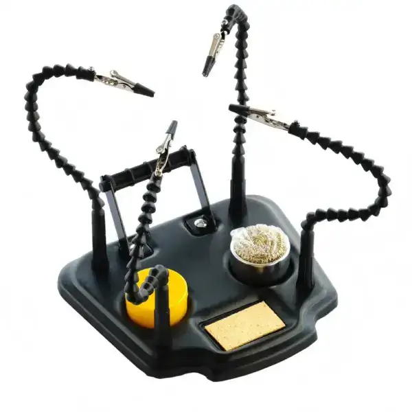 Image shows a soldering helping hands tool with adjustable arms, alligator clips, a sponge, and a soldering iron stand, designed to assist in precise soldering tasks.
