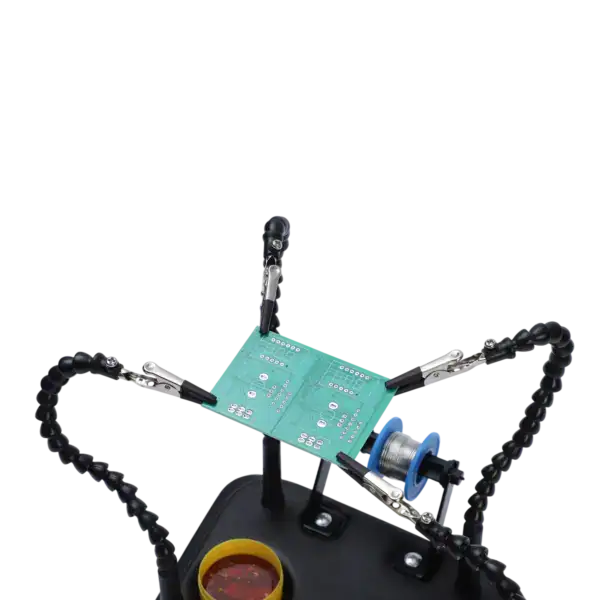 Close-up of helping hands tool holding a circuit board during soldering process, with adjustable arms and alligator clips providing stability for electronic component work.