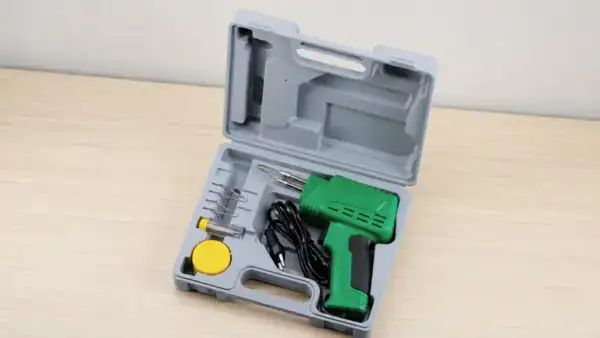 Green soldering gun with accessories in a plastic case, ideal for electronics repair and DIY projects.